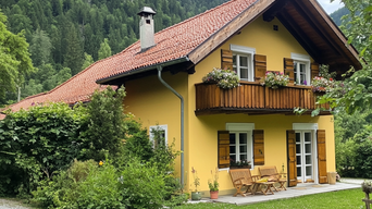 Gemütliches gelbes Landhaus mit Holzfensterläden, Balkon und Garten, umgeben von Bergen und Natur