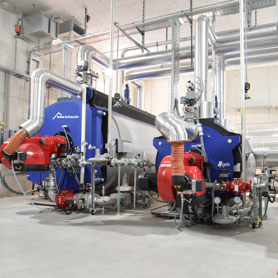 Großbrenner & Warmwasserkessel: Industrieanlagen von bösch in einem hohen grauen Raum | © Walter Bösch GmbH & CO KG
