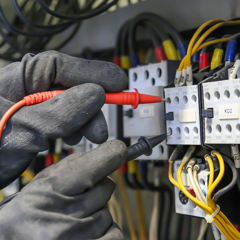 Elektrotechniker, der digitale Multimeter-Messgeräte verwendet, um die elektrische Stromspannung am Leistungsschalter in der Hauptstromverteilungsplatine zu überprüfen