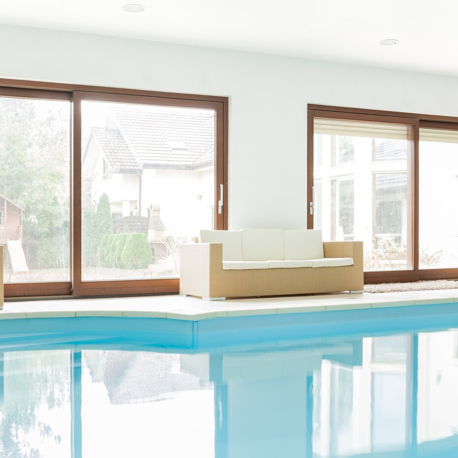 bösch optima pool Deckenlüftung weißes Hallenbad mit braunen Sofas und große Fenster mit Holzrahmen | © photographee.eu - Fotolia