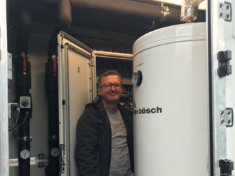 bösch Projekttechniker Johann Unger bei der Inbetriebnahme im Technikraum inklusive Schaltschrank, Warmwasser-Boiler, Puffer für Heizung und Kälteversorgung. | © bösch - heizung, lüftung, klima