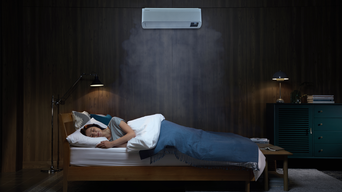 Frau schläft in dunklem Schlafzimmer, über dem Bett hängt eine Samsung Klimaanlage
