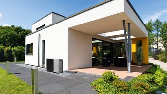 Modernes Flachdachhaus mit großzügiger Terrasse, Wärmepumpe im Außenbereich und gepflegtem Garten | © bösch heizung.klima.lüftung